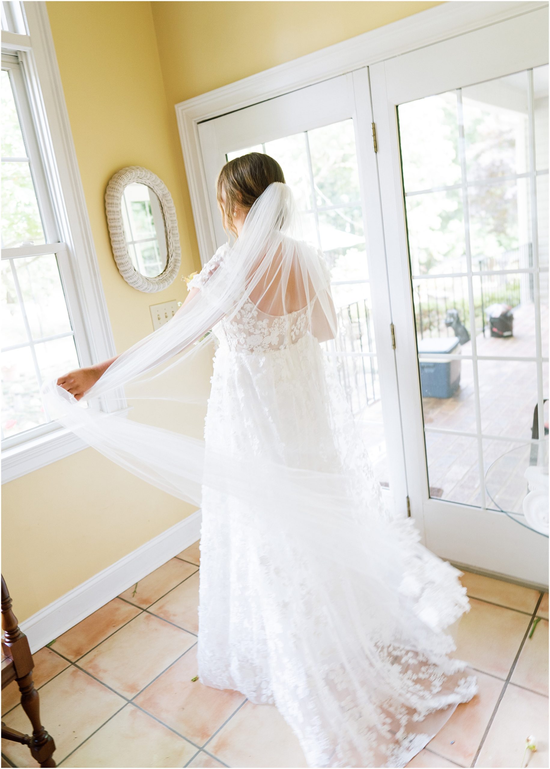 Brides with veil on spinning in her grandparents sunroom. Bride getting ready.