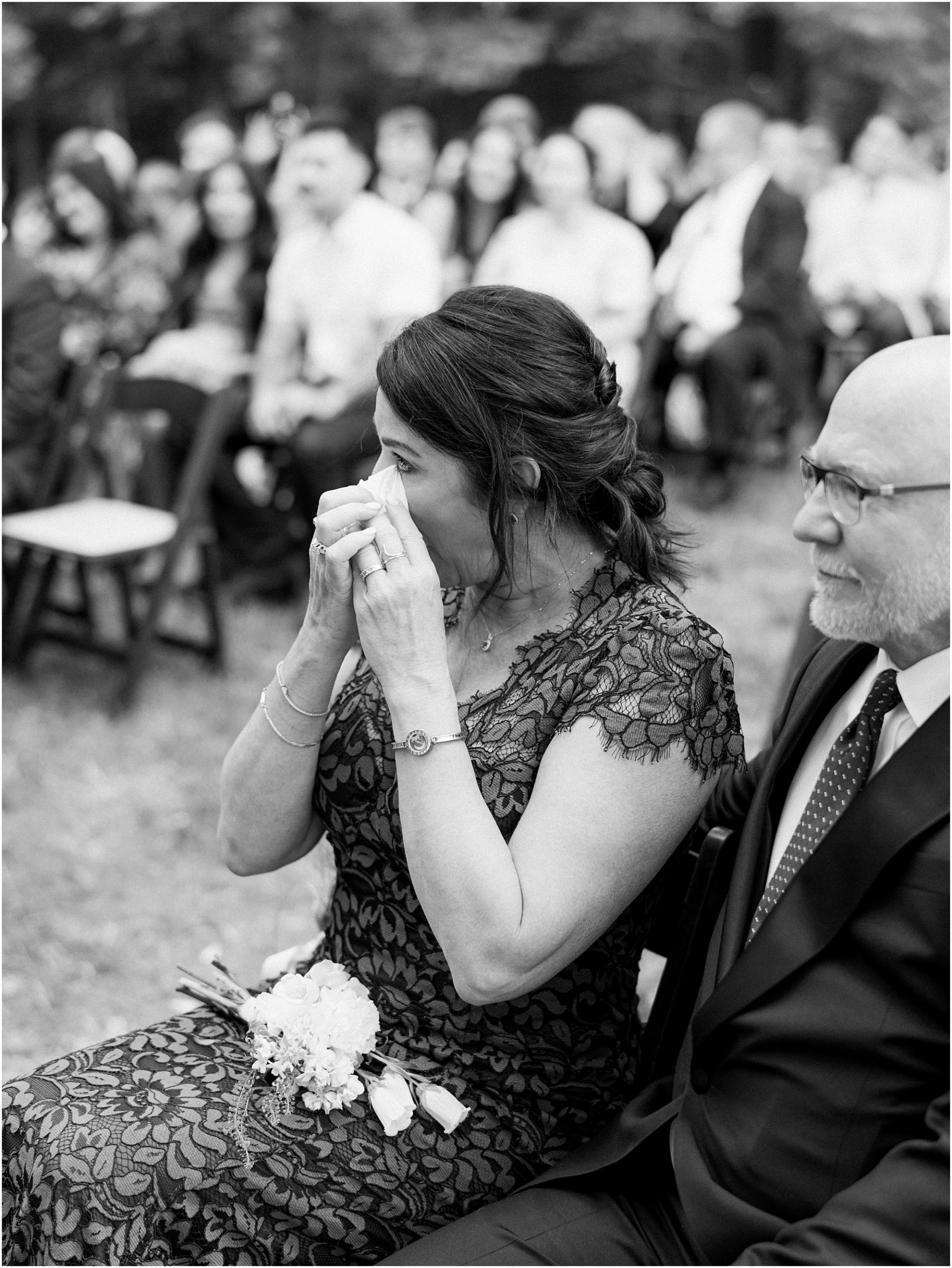 Mother of the bride tearing up as bride walks down aisle.