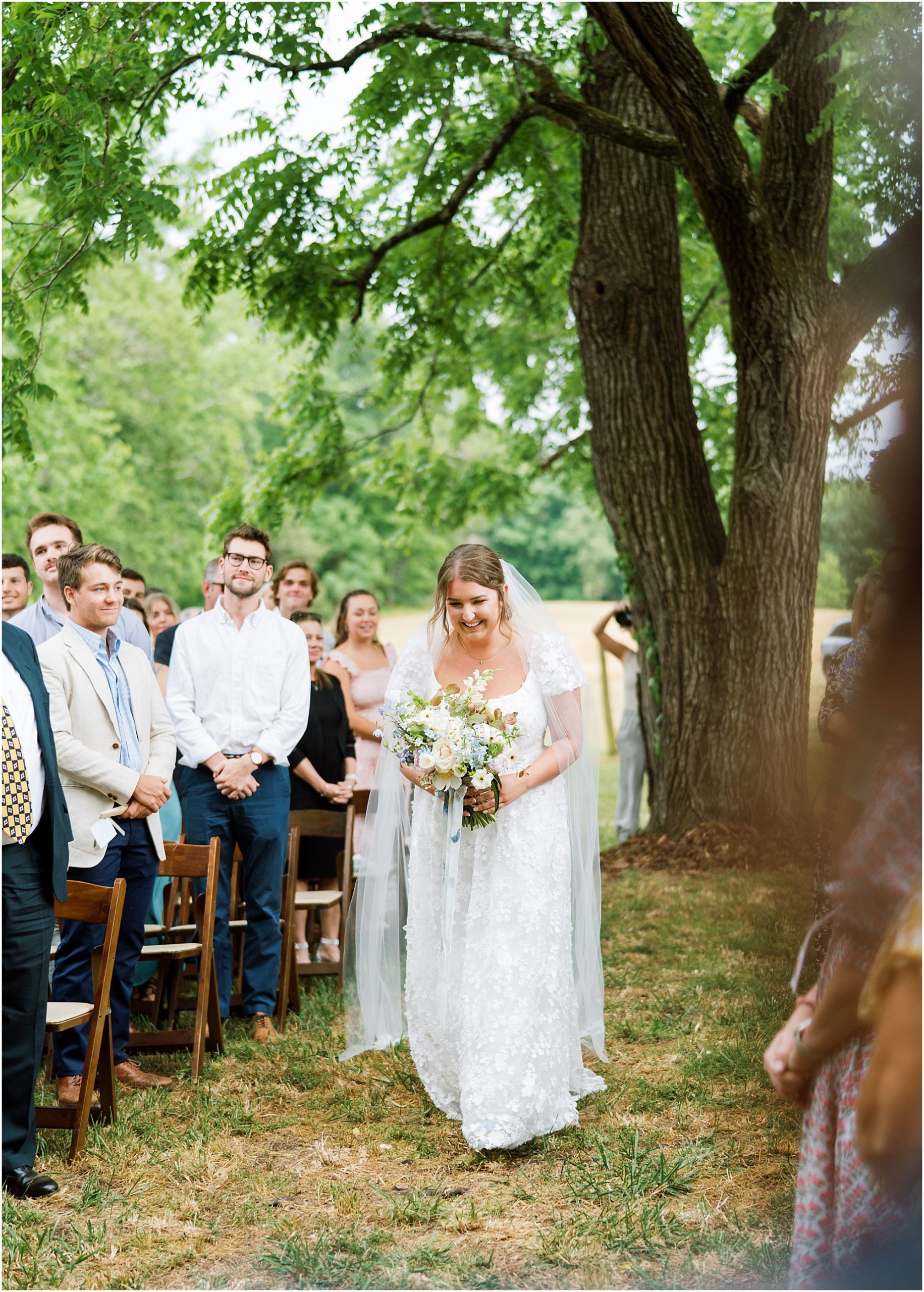 Bride walking down the aisle by herself with her wildflower bouquet she made herself.