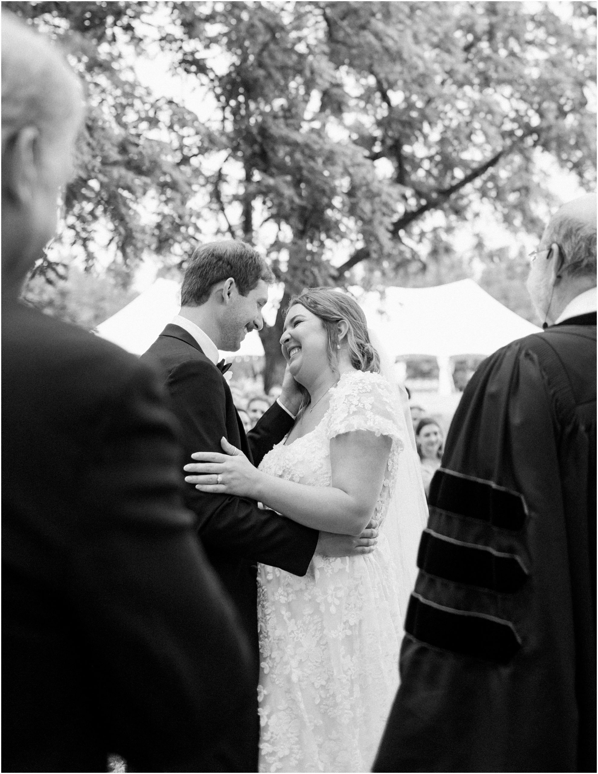 Bride and groom first kiss in black and white.