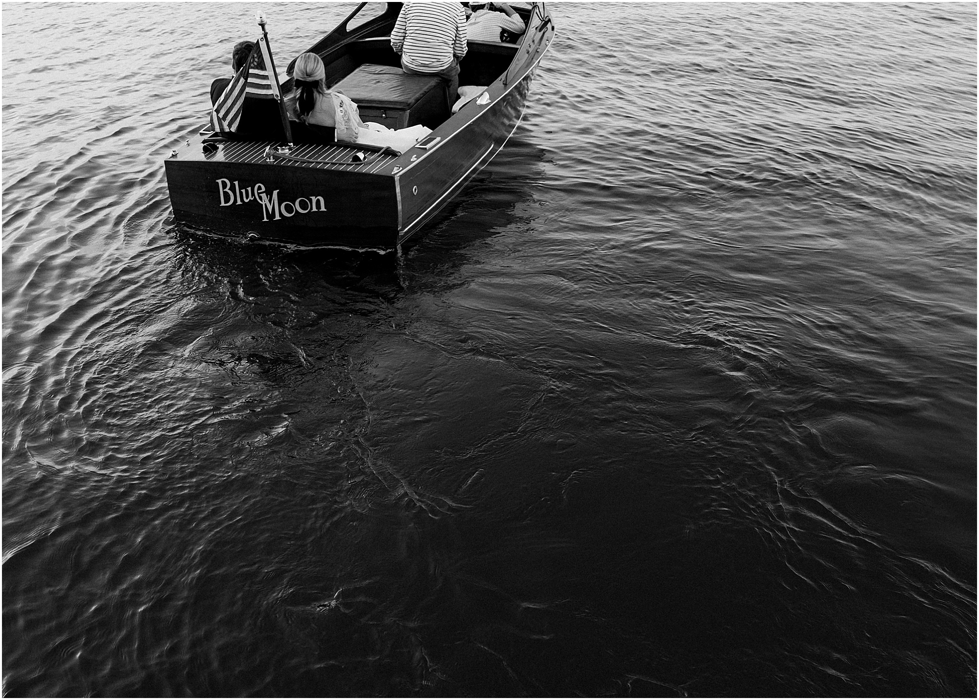 Bride and groom riding a boat to their wedding reception in black and white