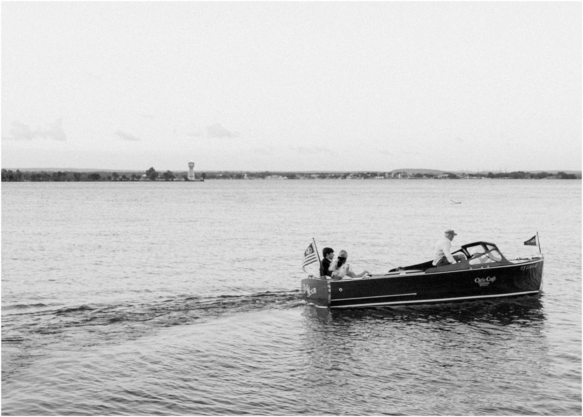 Bride and groom riding a boat to their wedding reception in black and white