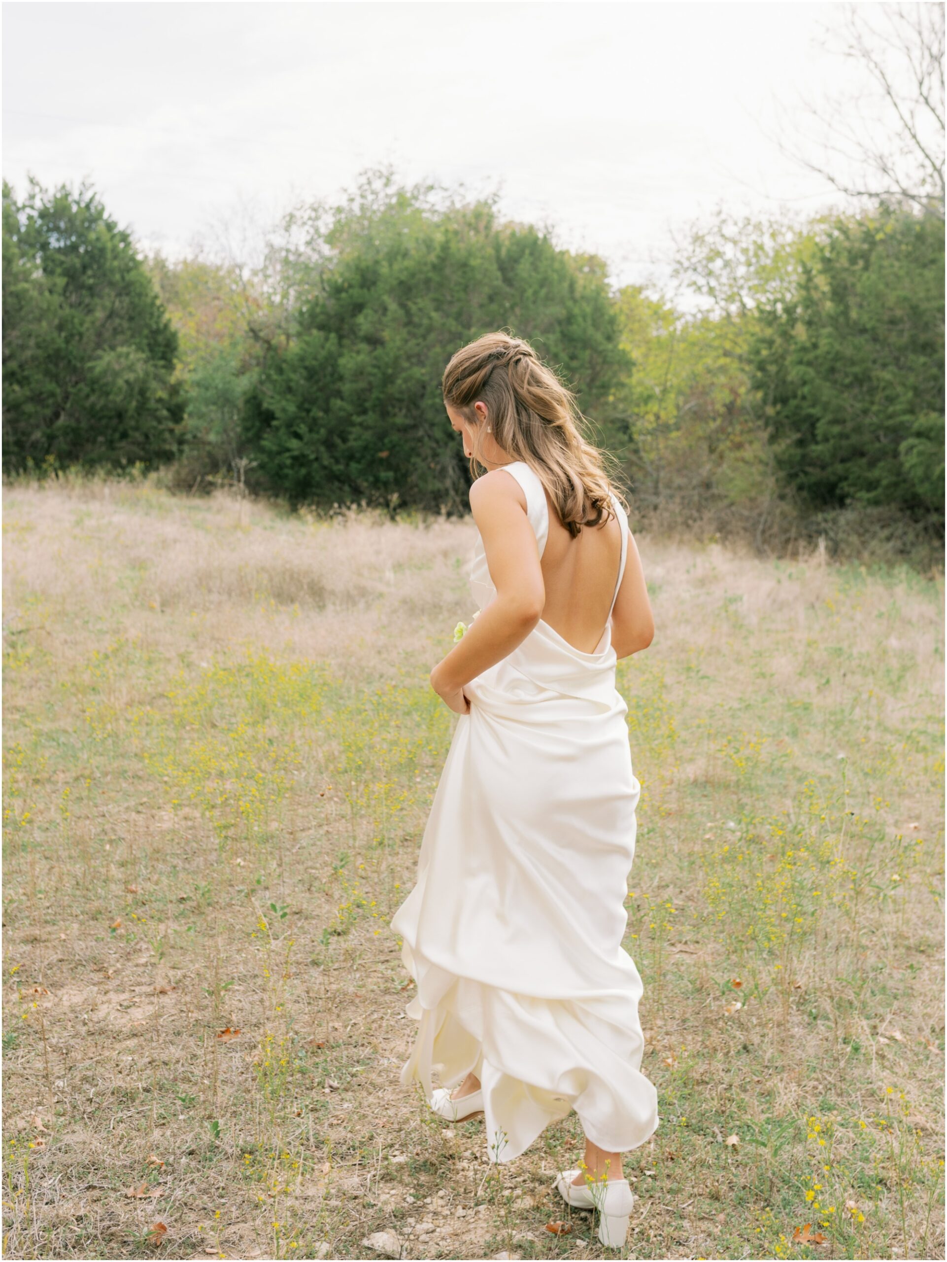 bride in danielle frankel dress in field from an elevated backyard wedding in fort worth, Texas