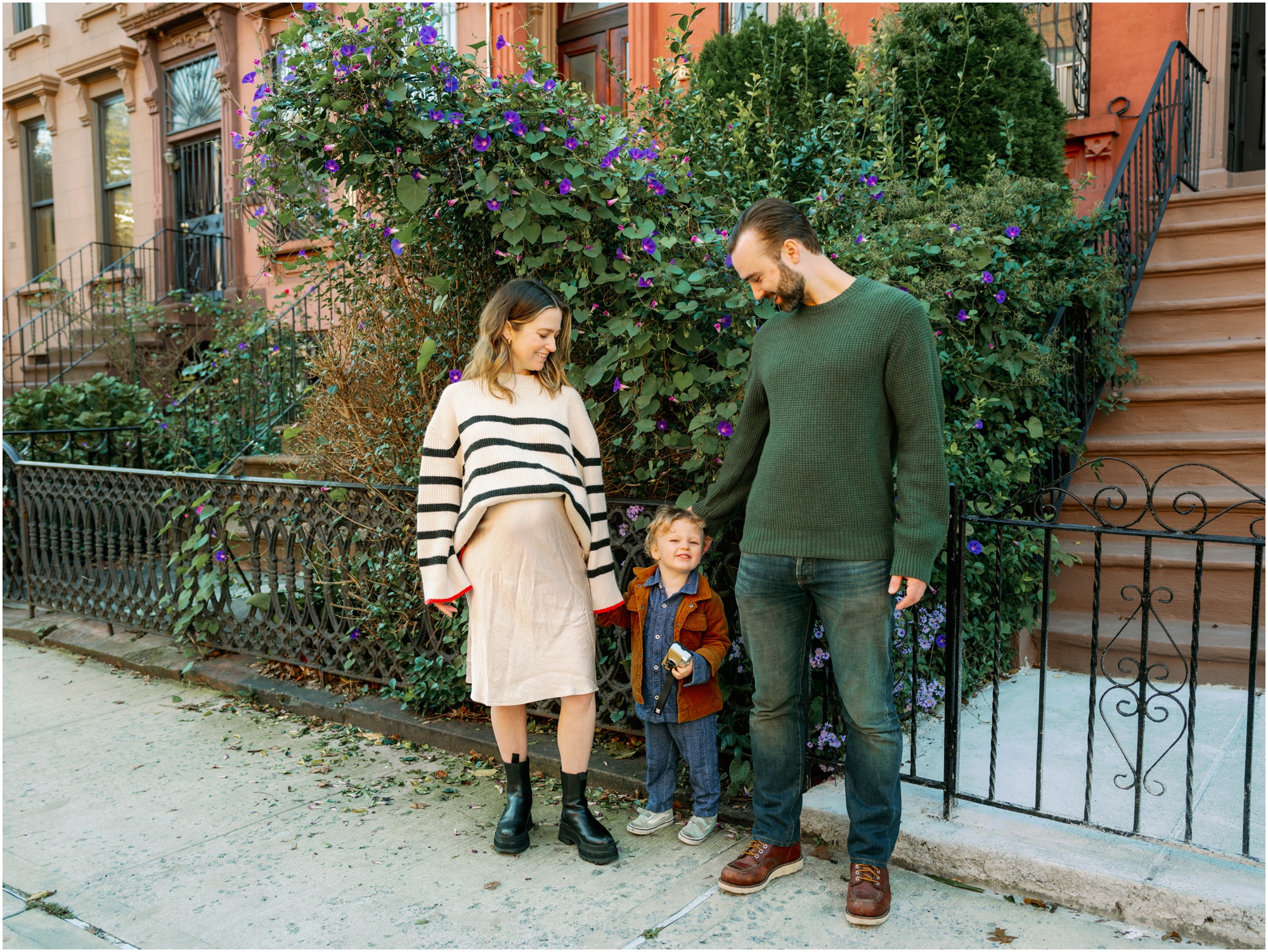 family of three stops for a photo on the sidewalk in Brooklyn, New York