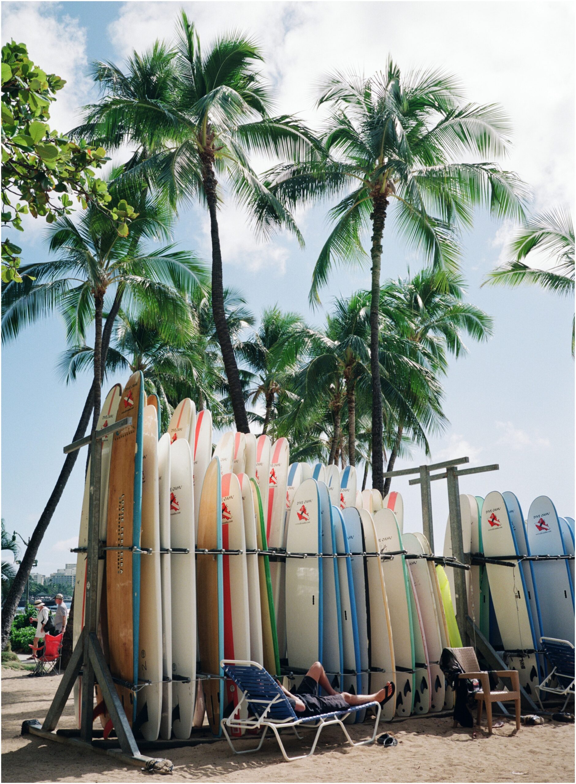 Waikiki Beach surfboards with a man sleeping under them on 120mm film