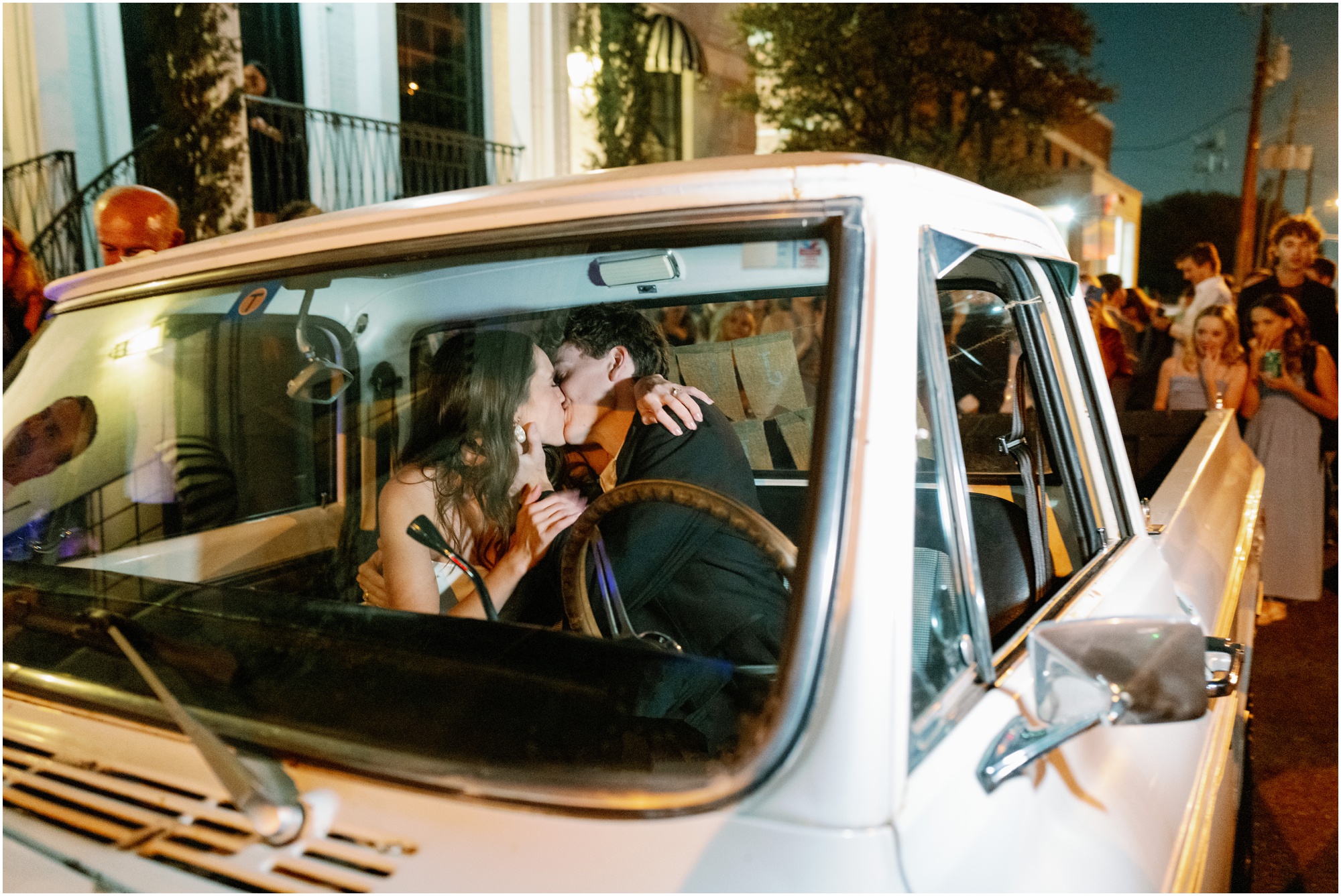 bride and groom kiss in truck after wedding reception